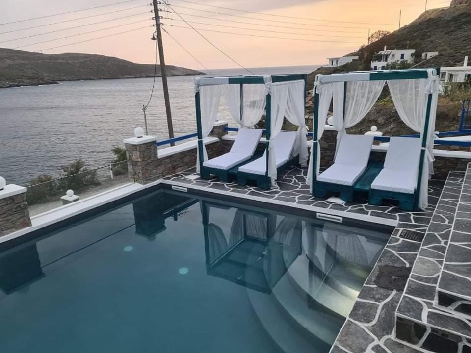 a swimming pool with two chairs and the water at Angel's Villa Sunset in Agios Dimitrios