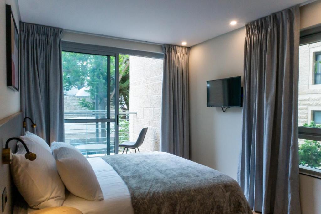 a bedroom with a bed and a large window at Urbanic Hotel in Jerusalem