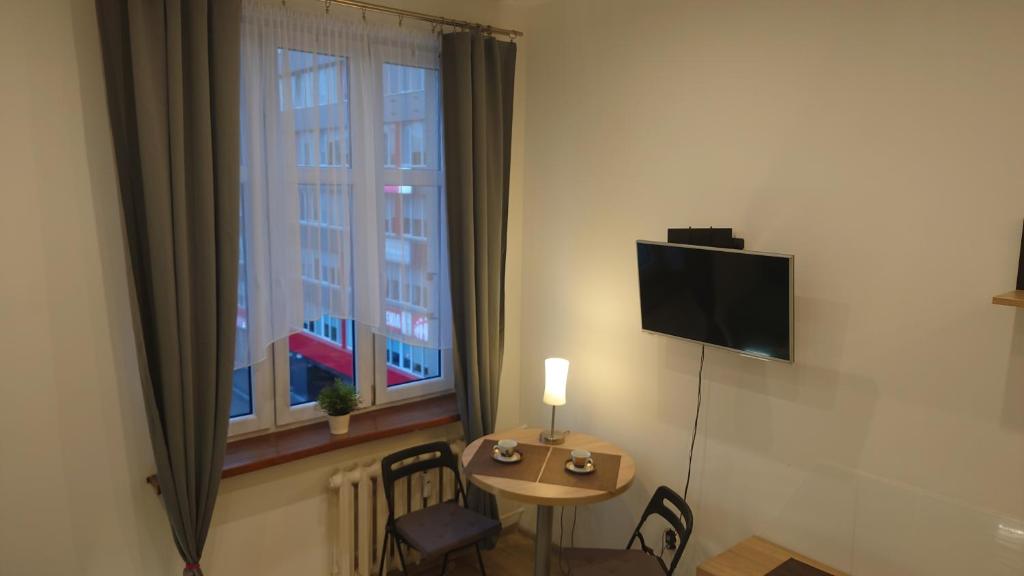 カトヴィツェにあるApartment Katowice City Centerのテーブル、テレビ、窓が備わる客室です。