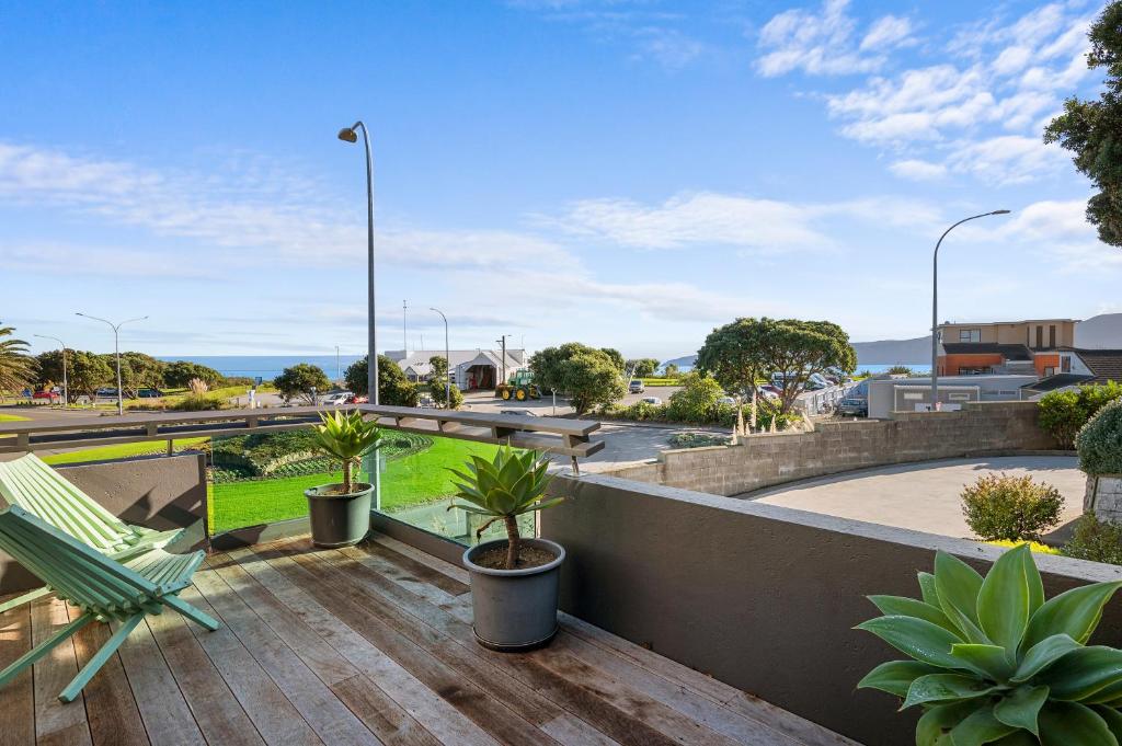a deck with a chair and some plants on it at APARTMENT 4A - By the Beach in Paraparaumu Beach