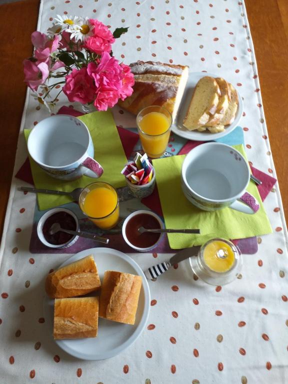 une table avec une assiette de pain et deux verres de jus d'orange dans l'établissement La chambre Lomen, à Lauzach