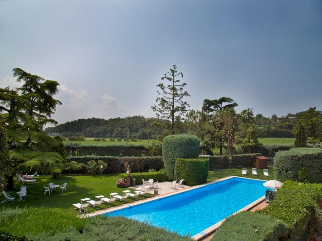a swimming pool in a garden with chairs and trees at Veronello Resort in Bardolino