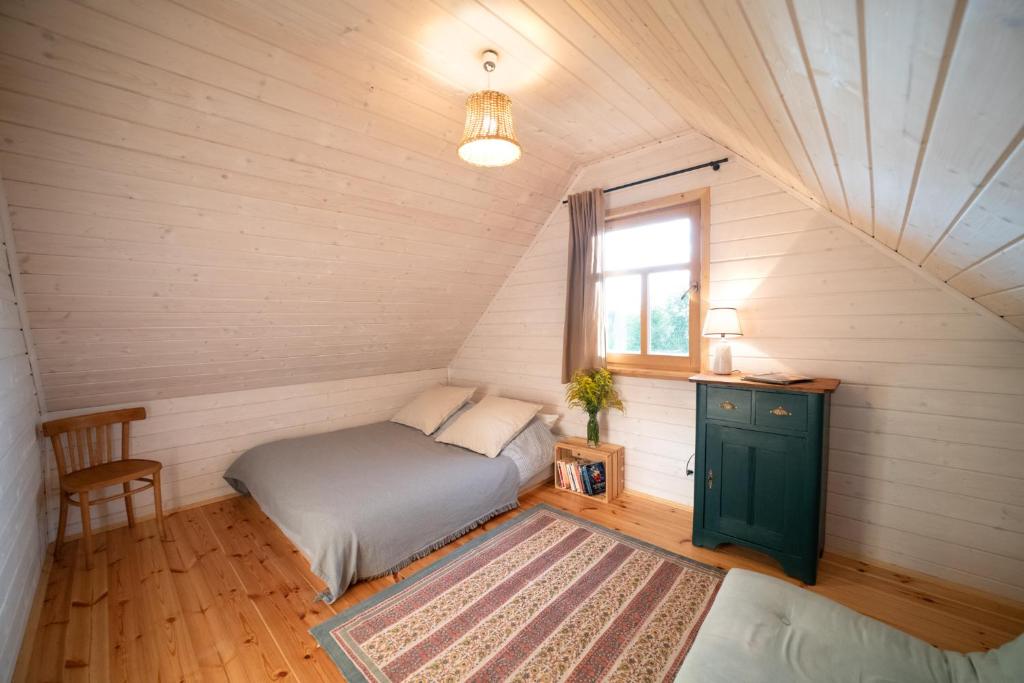 a bedroom with a bed and a window in a attic at Dalej Nie Idę in Buda Ruska