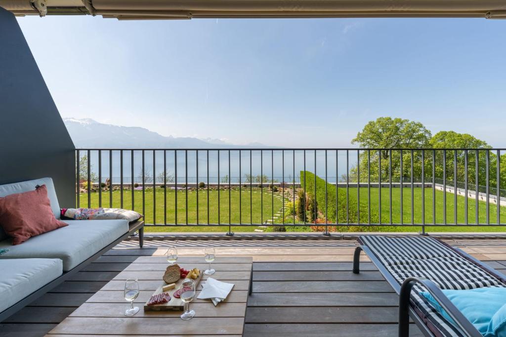 a balcony with a couch and a view of the ocean at Les Terrasses de Lavaux 1 - Appartement de luxe avec vue panoramique et piscine in Puidoux