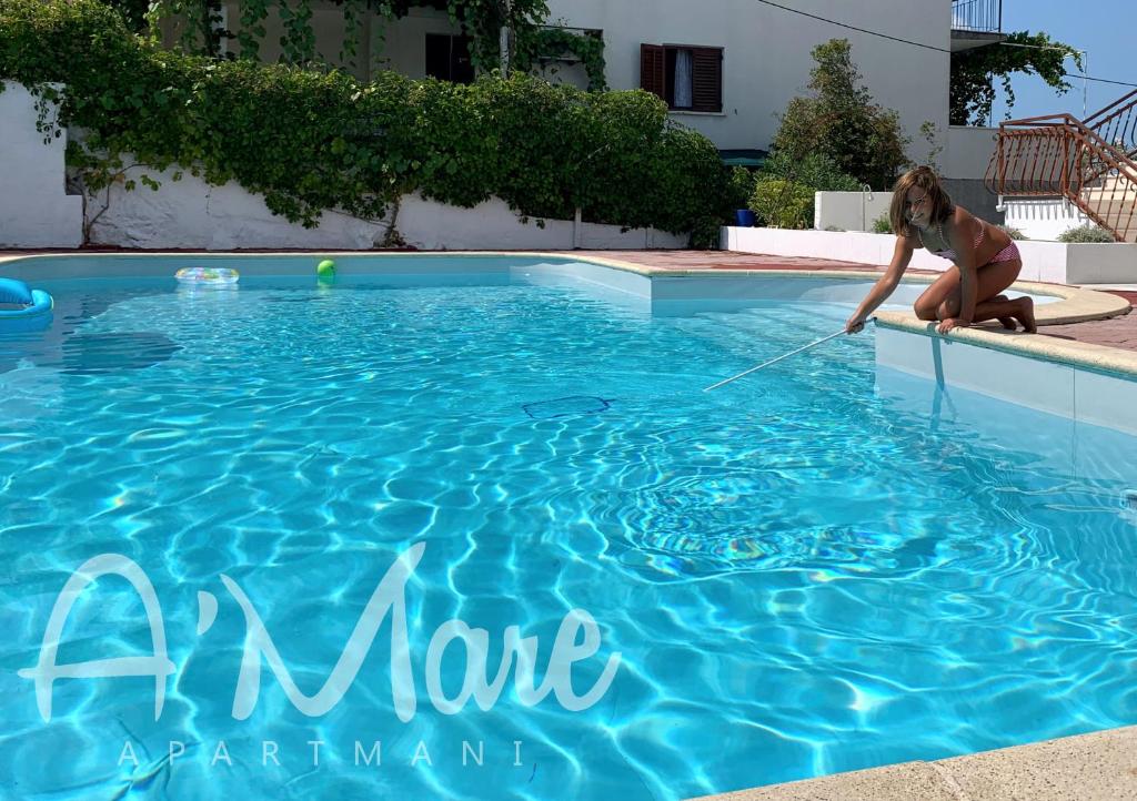una mujer está jugando con una manguera de agua en una piscina en Villa A'Mare en Seget Vranjica