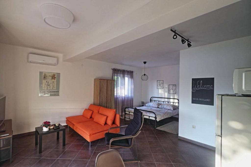 uma sala de estar com um sofá laranja e uma cama em Apartman Studio Pesja em Omišalj