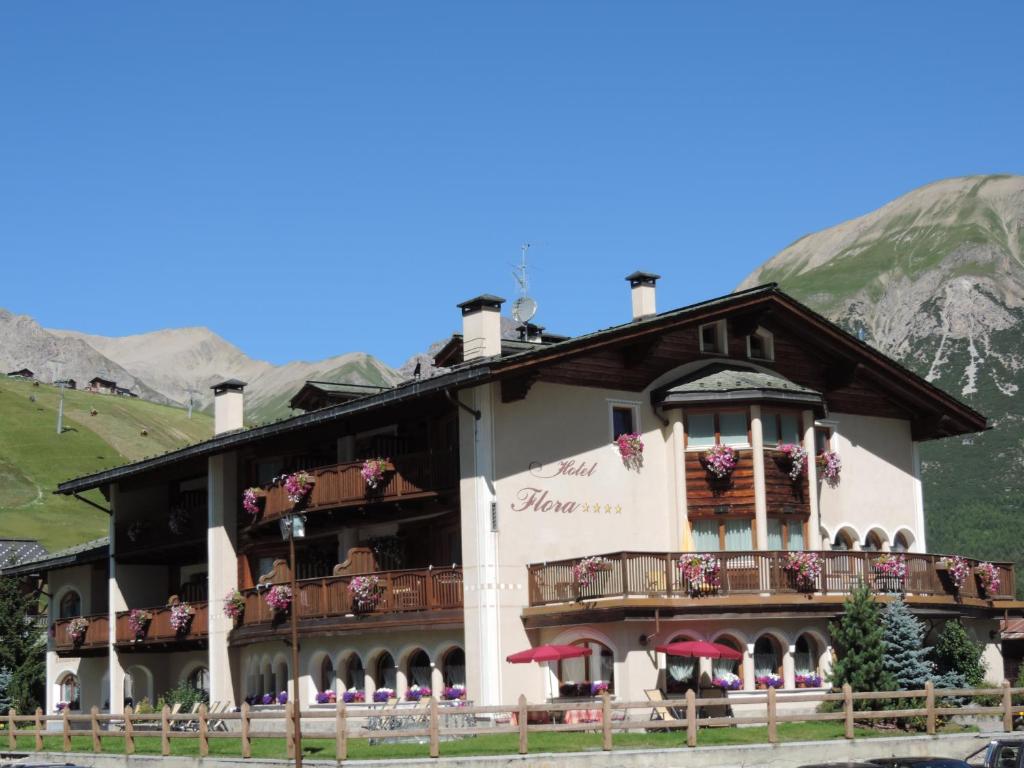 a building with a balcony and a mountain at Hotel Flora in Livigno