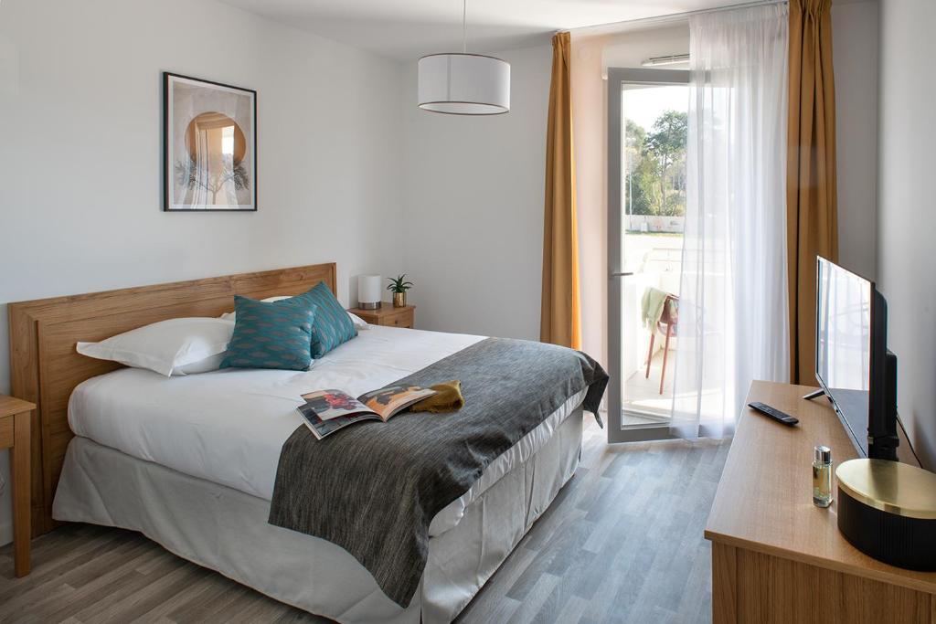 een slaapkamer met een bed, een bureau en een televisie bij DOMITYS LES TOURMALINES in Carpentras