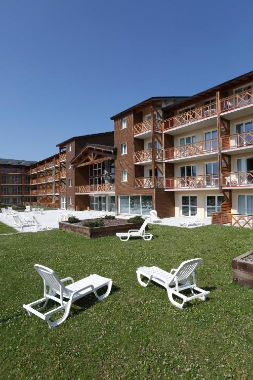 two lounge chairs on the grass in front of a building at Vacancéole - Appart'Vacances Pyrénées 2000 in Bolquere Pyrenees 2000