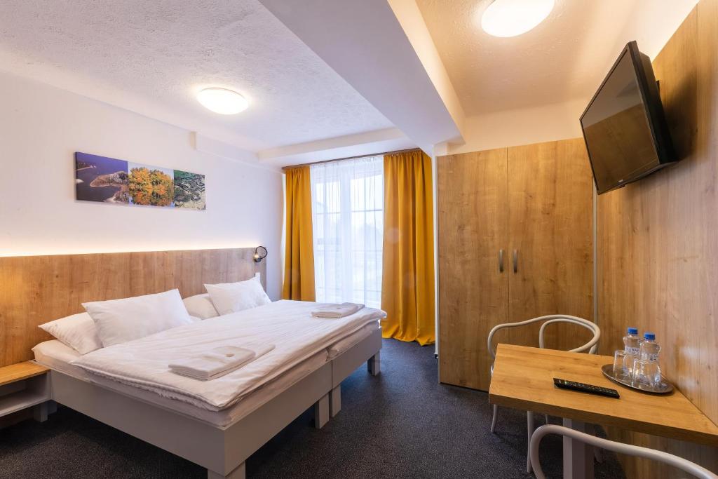 a bedroom with a bed and a tv and a table at Hotel Svět in Třeboň