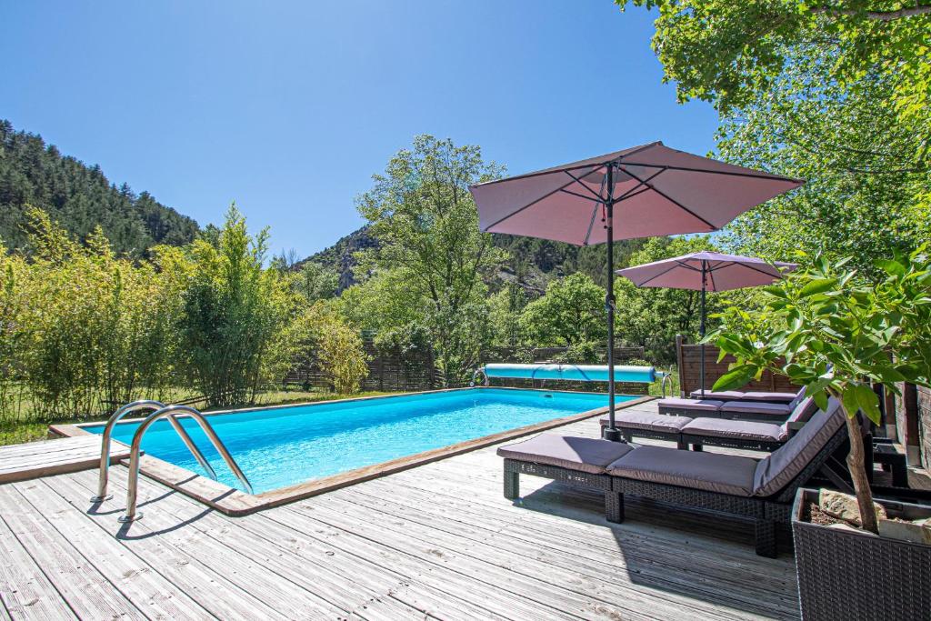 une piscine avec deux chaises longues et un parasol dans l'établissement Le Foulon en Baronnies, à Buis-les-Baronnies