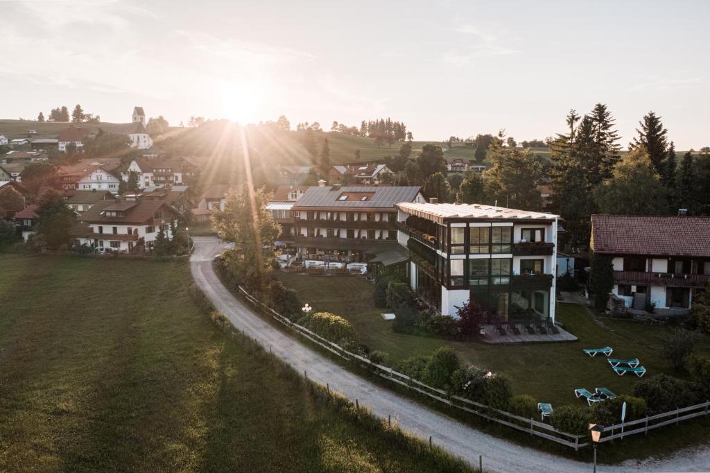 an aerial view of a town with a house and the sun at Mittelburg Wellnesshotel in Oy-Mittelberg