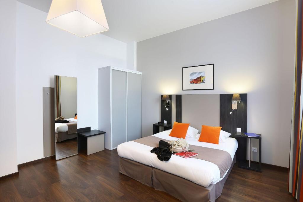 - une chambre avec un grand lit et des oreillers orange dans l'établissement Odalys City Toulouse Colombélie, à Toulouse