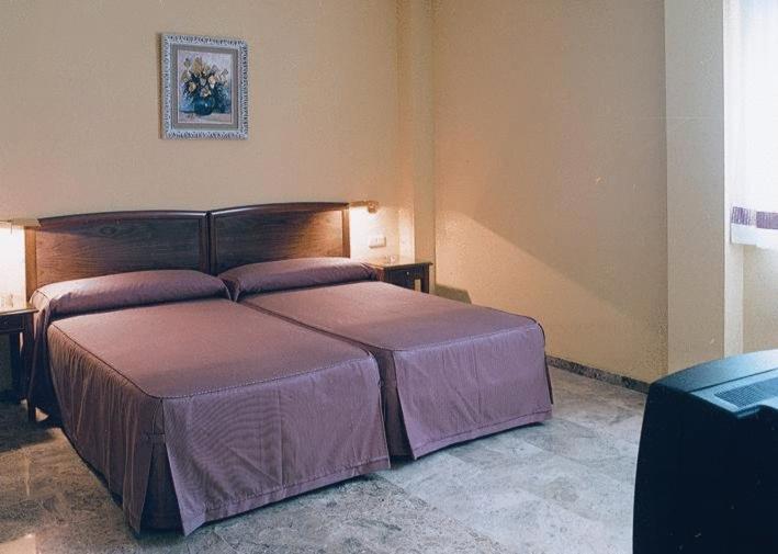 um quarto com uma cama grande e lençóis roxos em Hotel Isabel em Almussafes