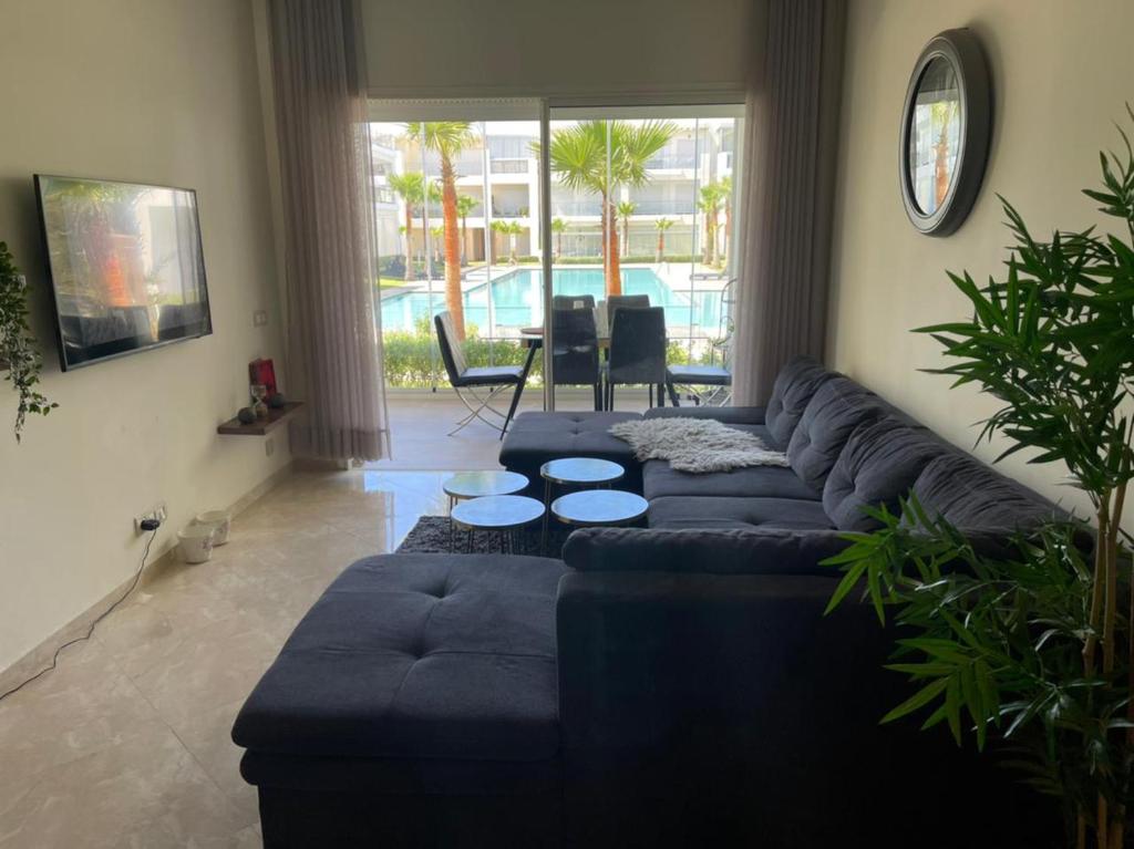 ein Wohnzimmer mit einem blauen Sofa und einem Tisch in der Unterkunft Appartement vue piscine bien équipé et bien ensoleillé in Casablanca