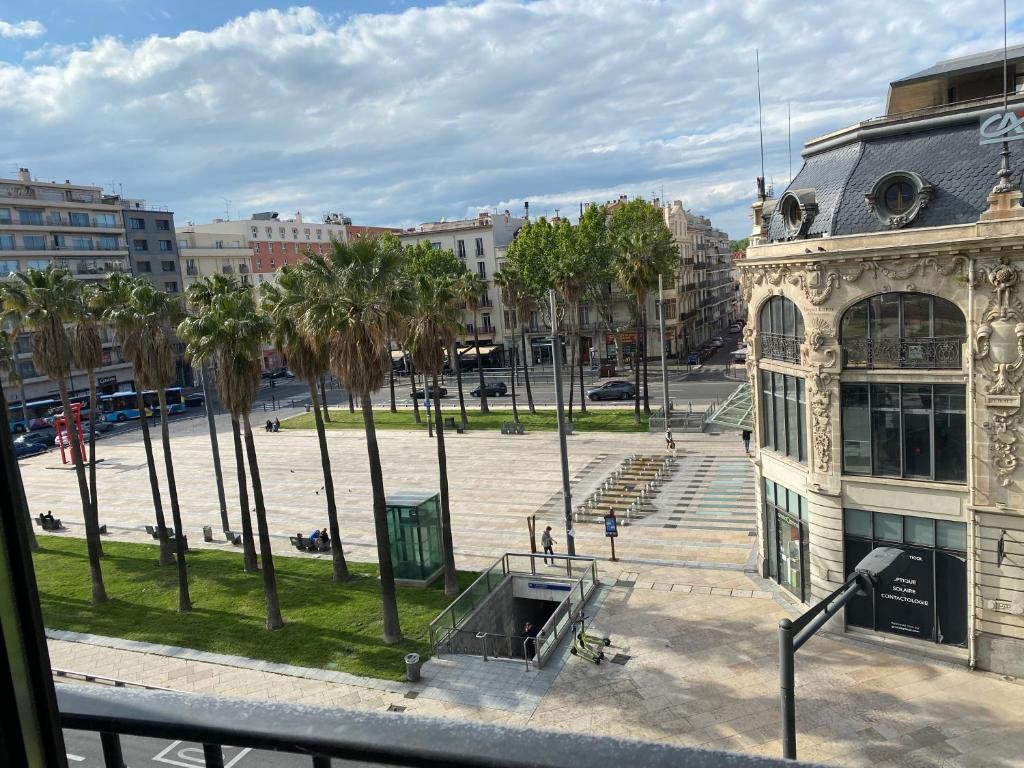 - une vue sur un parc avec des palmiers et un bâtiment dans l'établissement Appartement d’artiste lumineux central 76m2, à Perpignan