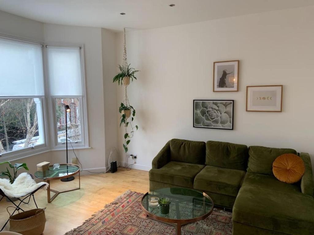 a living room with a green couch and a table at Lovely spacious 1-bedroom flat in Tufnell Park close to Central London in London