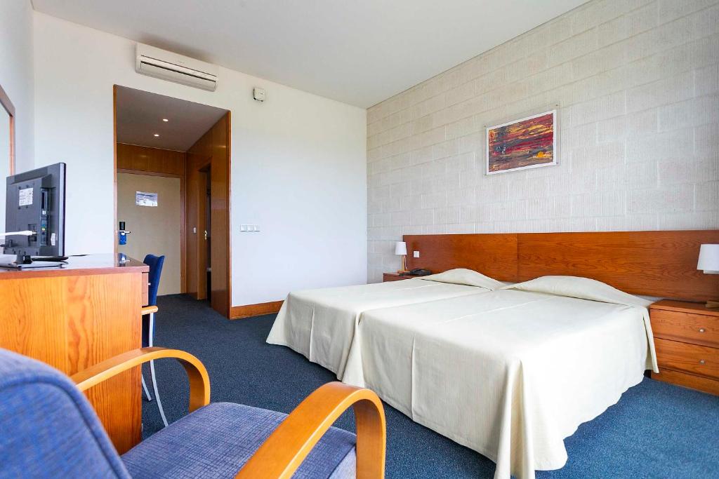 a hotel room with two beds and a television at Hotel Colombo in Vila do Porto