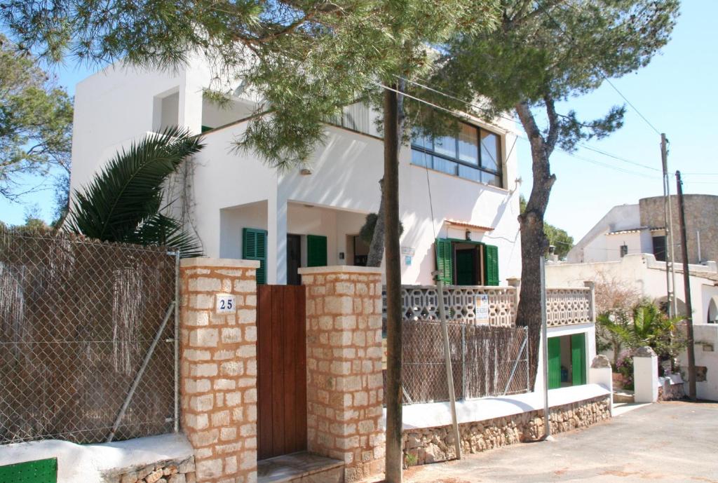 una casa blanca con una valla y un árbol en Casa Maria Elena, en Cala Santanyi