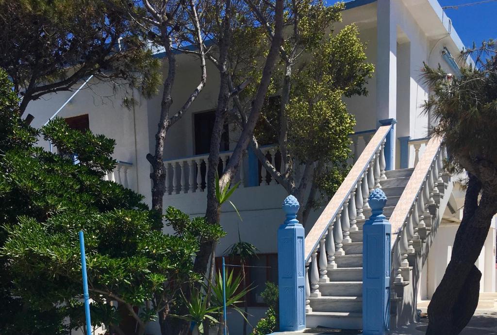 a white house with blue stairs and trees at Panorama Studios in Lipsoi