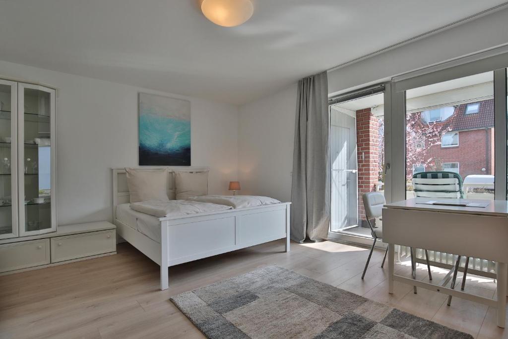 een witte slaapkamer met een bed en een bureau bij Am Elchgrund Am Elchgrund 7 Appartement 2 in Timmendorfer Strand