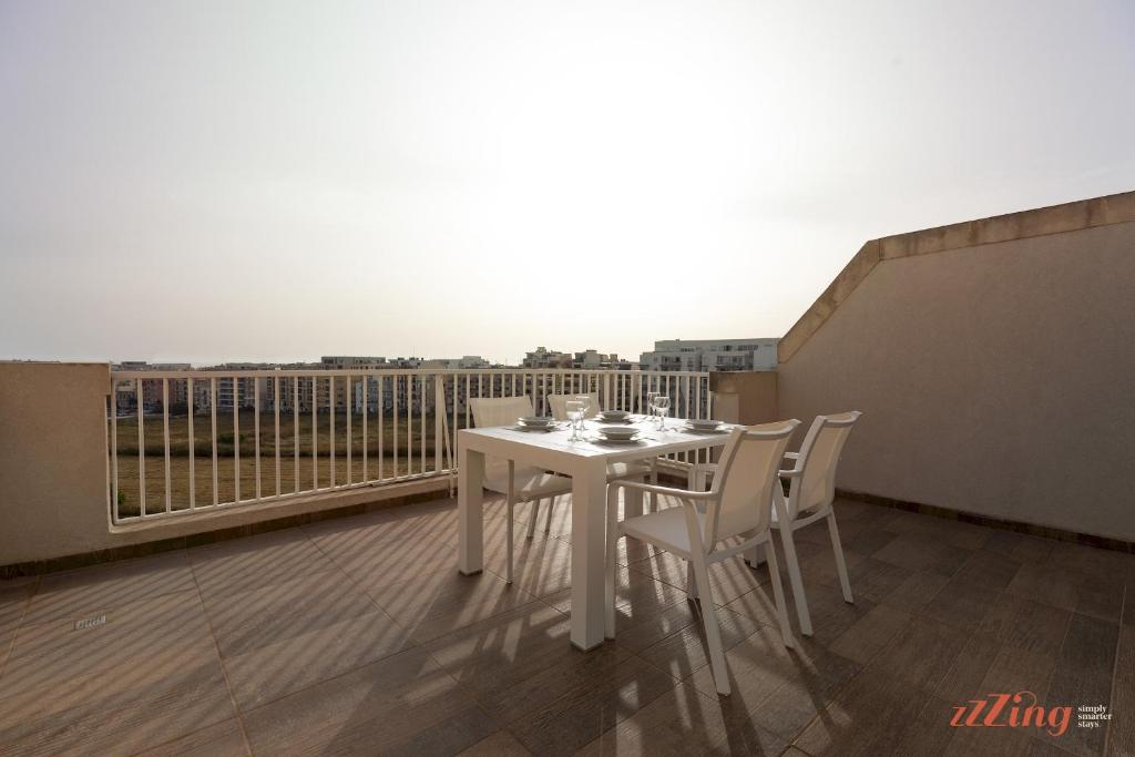 d'une table et de chaises blanches sur un balcon. dans l'établissement Sunny Penthouse wTerrace and Open Views, à San Pawl il-Baħar