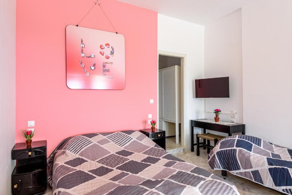 a bedroom with two beds and a pink wall at Angela Apartments new listing in Marathi