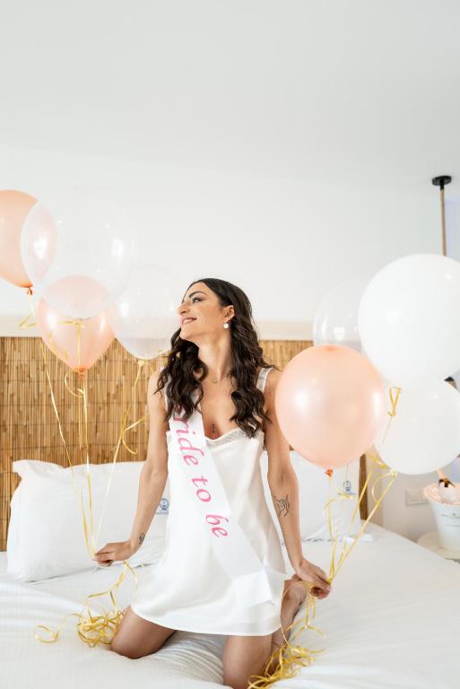 a woman sitting on a bed with balloons at Blue Harbour Boutique in Ayia Napa