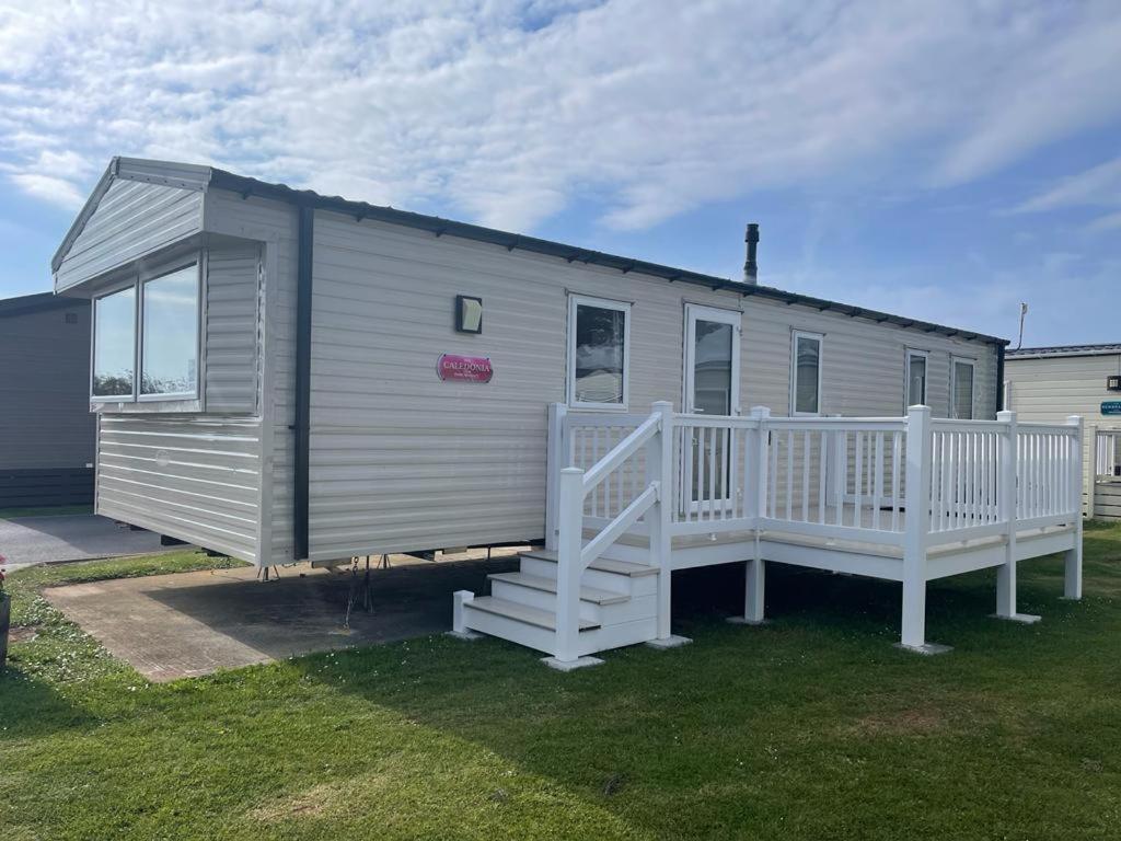 a mobile home with a porch and a white railing at Sea Wagon Caravan in Brixham