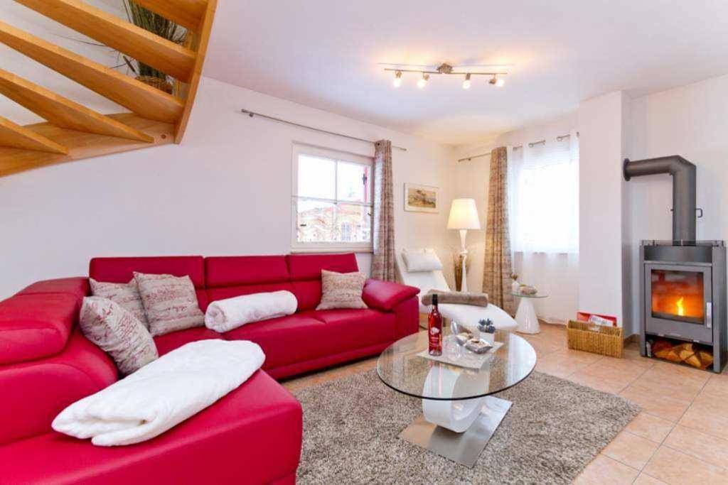 a red couch in a living room with a fireplace at Ferienhaus Reethaus Koserow in Ostseebad Koserow