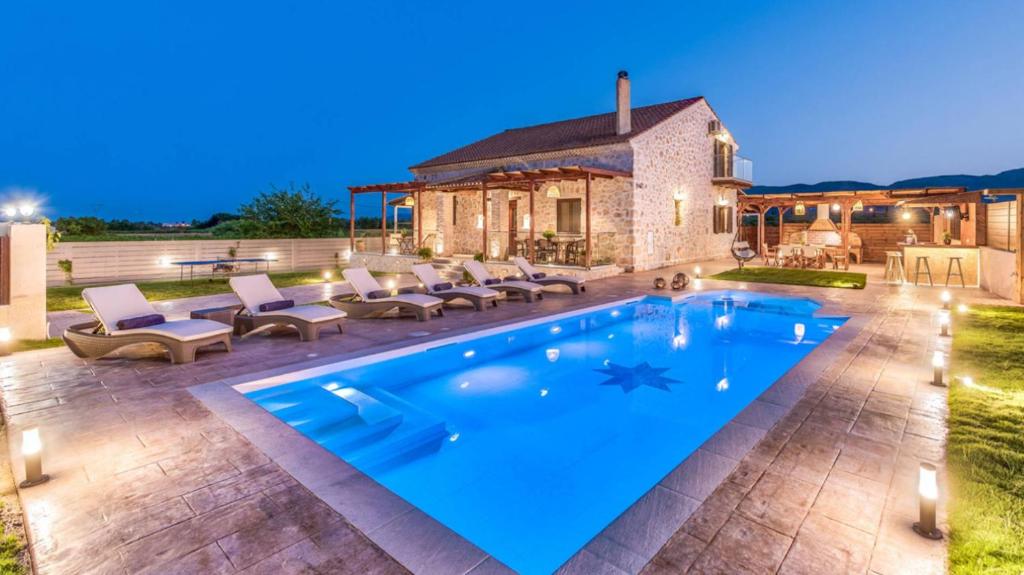 a swimming pool in a yard with chairs and a house at Zante Poolside Paradise - La Vite Stone Villa in Kalipádhon