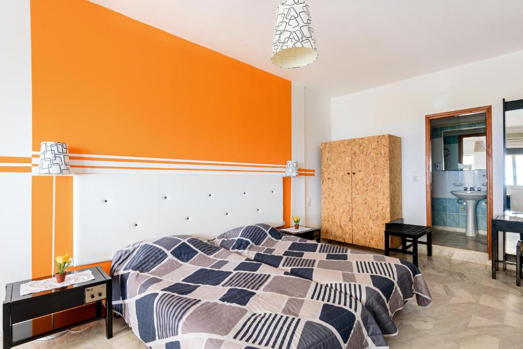 a bedroom with a bed and an orange wall at Angela Apartments new listing in Marathi