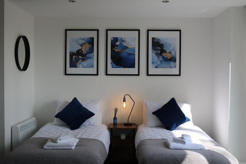 2 Betten in einem Zimmer mit vier Bildern an der Wand in der Unterkunft Wolverhampton - Gated Parking - George House in Wolverhampton