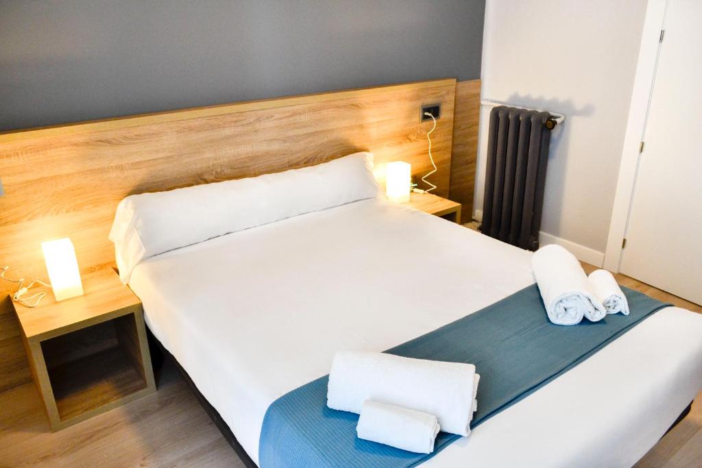 sypialnia z dużym białym łóżkiem i 2 ręcznikami w obiekcie Alda Centro León w mieście León