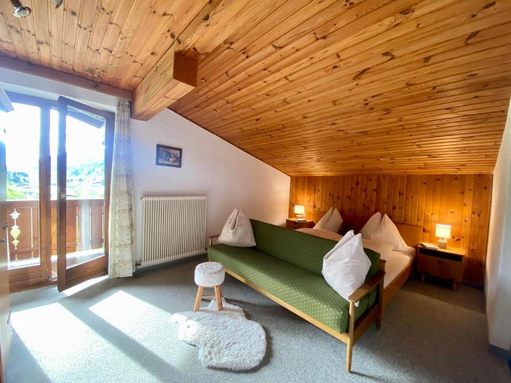a living room with a green couch and a wooden ceiling at Ferienwohnung 4 in Taxenbach