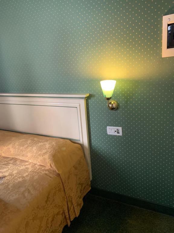 1 dormitorio con papel pintado de lunares y una luz en la pared en Locanda Ruga Rialto, en Venecia