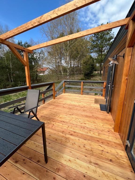 una terraza de madera con una mesa y una silla en una casa en Kaszubskie Pole, en Gowidlino