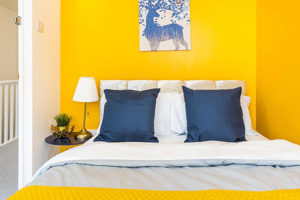 a yellow bedroom with a bed with blue pillows at Inglewood Hub in London