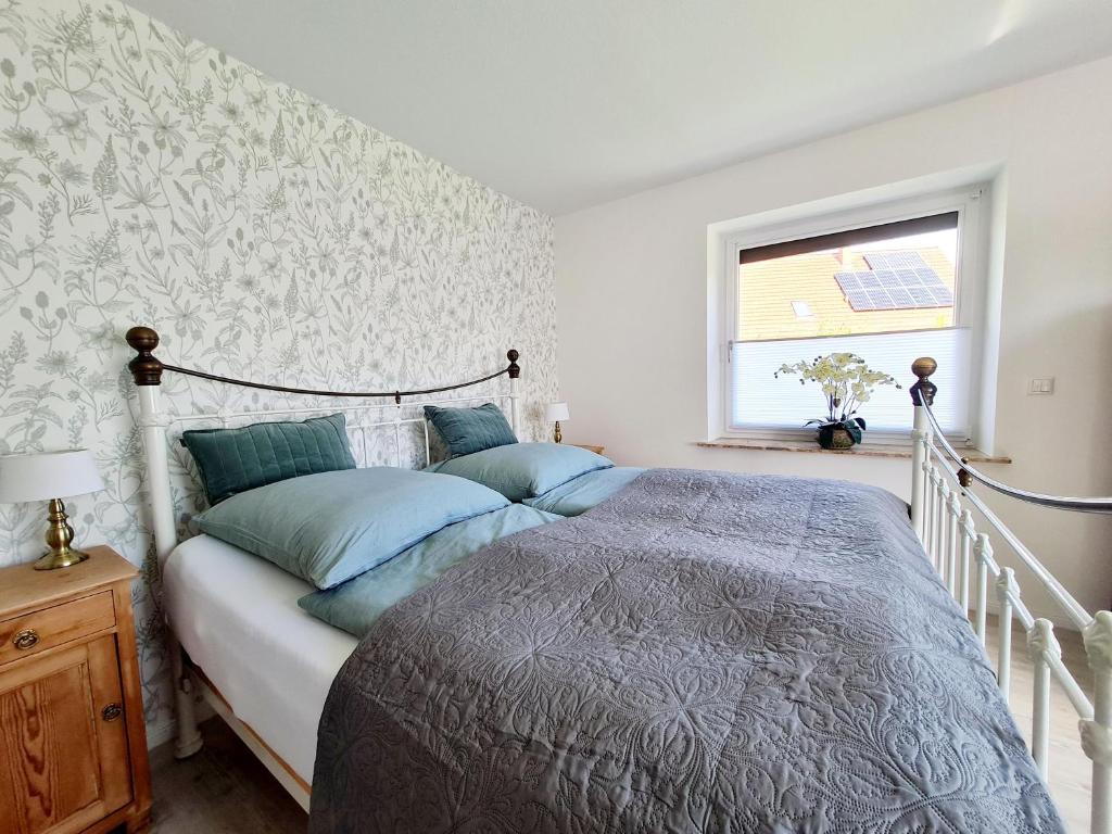 Un dormitorio con una cama con almohadas azules y una ventana en Ferienhaus Vergissmeinnicht, en Garding