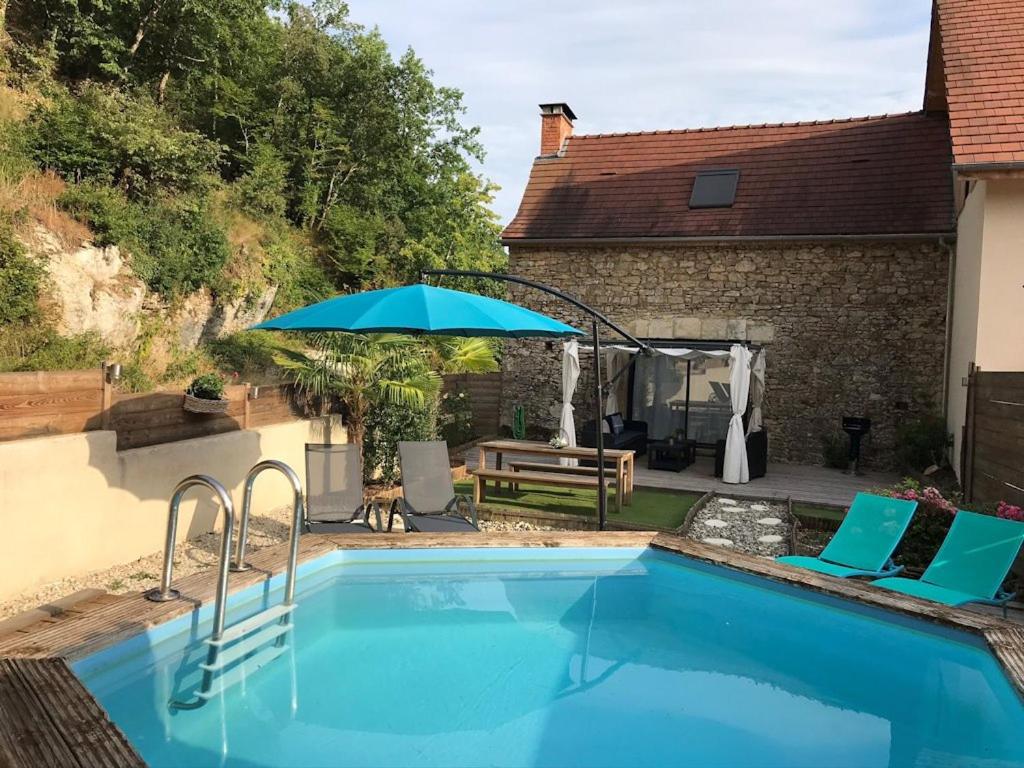 a swimming pool with an umbrella next to a house at Maison de Charme l Etoile in Saint-Vincent-de-Cosse