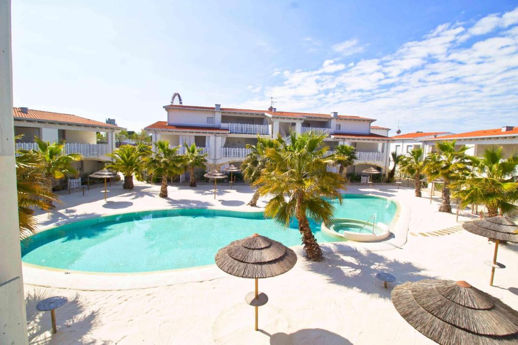 una piscina con sombrillas y palmeras frente a un hotel en Cala Blu en Lido di Jesolo