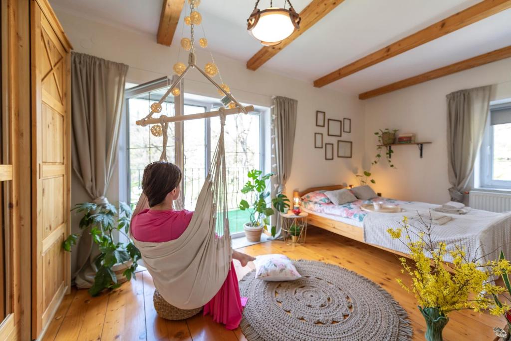 a woman sitting in a hammock in a bedroom at Apartament Boheme in Lądek-Zdrój