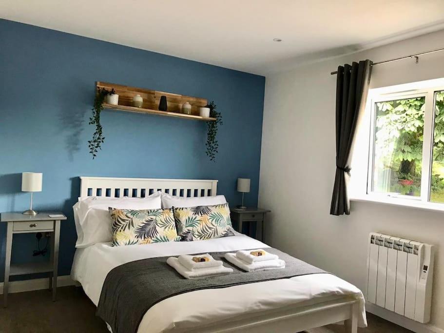 a blue bedroom with a bed with towels on it at Beautiful cosy rural retreat with parking! in Winford