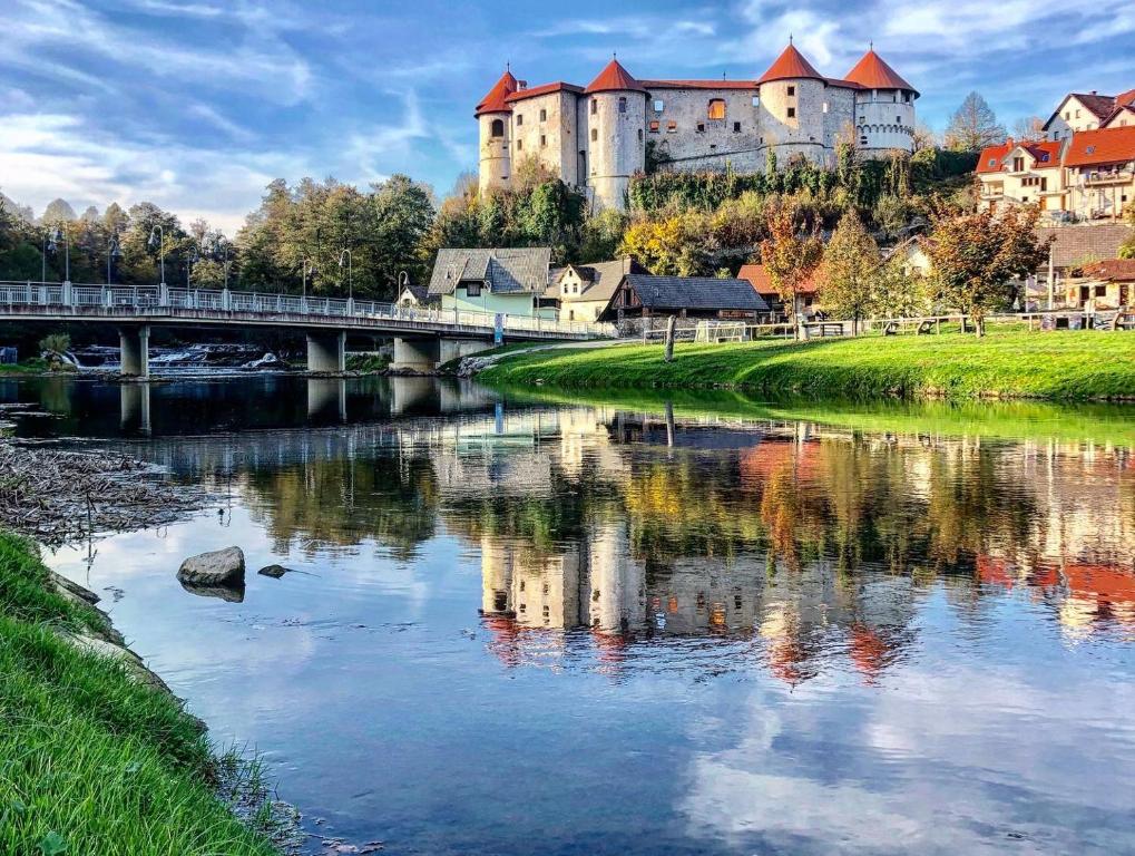 Gostišče Koren في Žužemberk: قلعة على تلة بجوار نهر