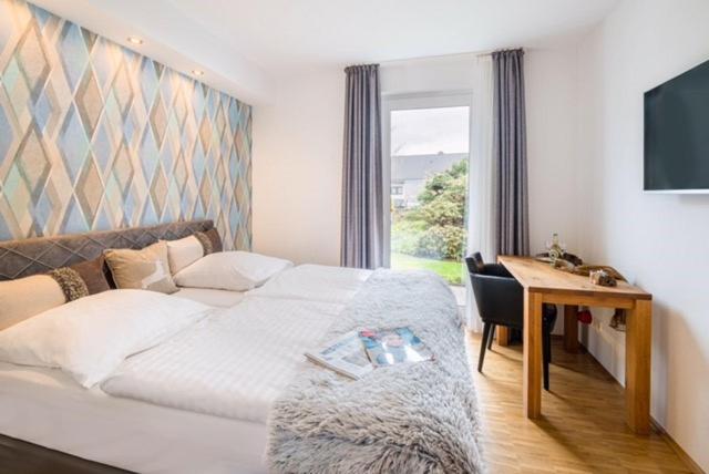 a bedroom with a bed and a desk and a television at BB Landhotel Hütter in Meschede