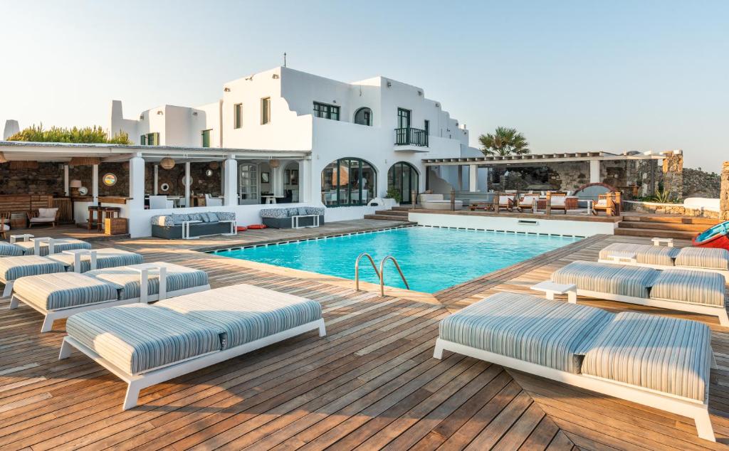 a villa with a swimming pool with chaise lounge chairs at Tharroe of Mykonos Boutique Hotel in Mikonos
