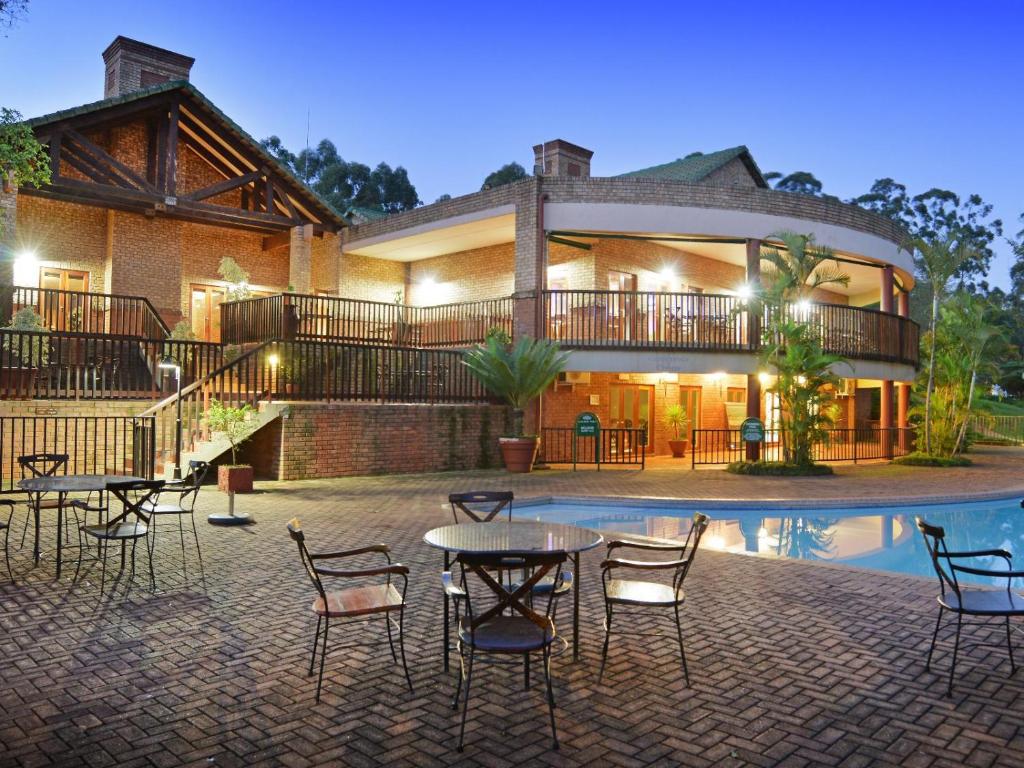 a house with a table and chairs in front of a pool at Greenway Woods Accommodation in White River