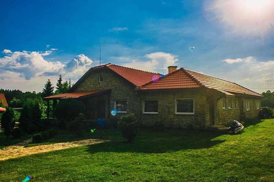 una casa con un césped verde delante de ella en Domek letniskowy w leśnym zaciszu en Węgorzewo