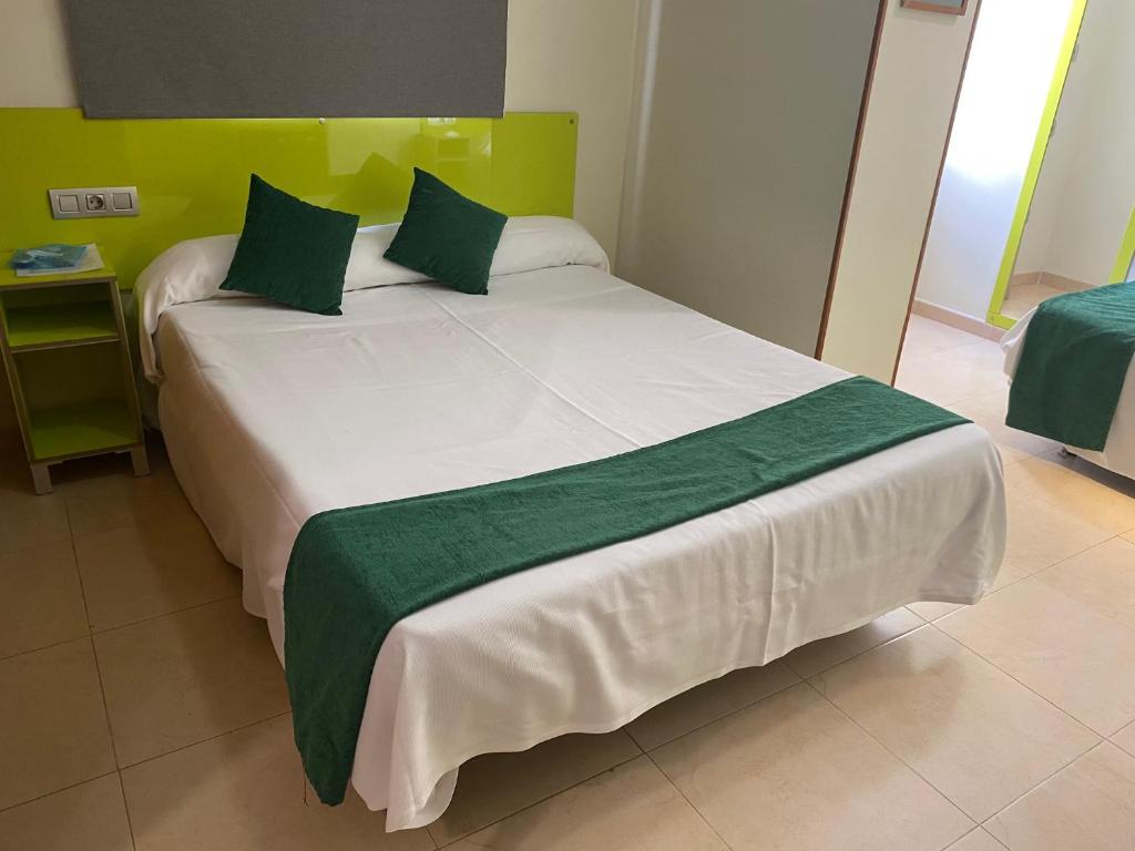 a bedroom with a large white bed with green accents at Hotel Andrea´s in Los Cristianos