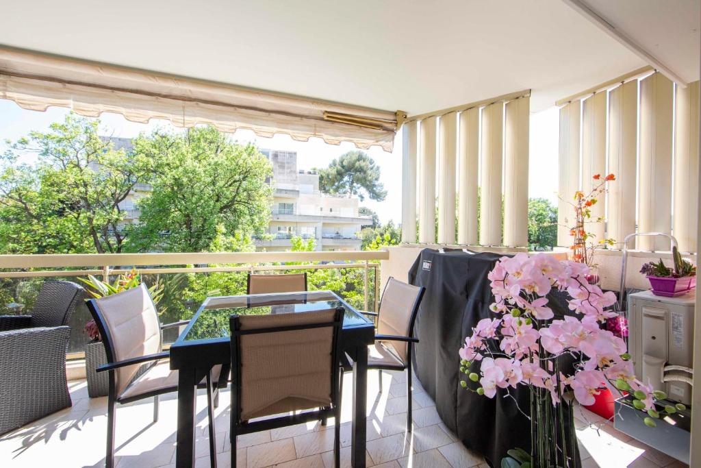 einen Balkon mit einem Tisch, Stühlen und Blumen in der Unterkunft Ideal congress and vacation LIVE IN VILLA PARADOR in Cannes